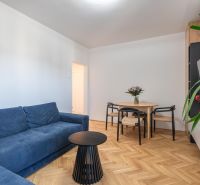 Living room with a blue sofa, table, and wooden decor flooring in a 3-room apartment.