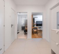 A hallway with white walls and entrances to the kitchen and living room in a three-room apartment.