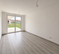 A spacious room with large windows and a wooden decor floor in a family house.