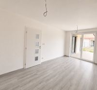A bright room with wood-patterned flooring and large windows in a family house.
