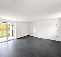 A spacious room with a large window and dark tiles in a family house.