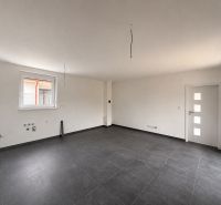 A bright room with dark ceramic tiles and a large window in a family house.