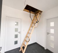 The interior of a family house with a foldable staircase to the attic and white doors.