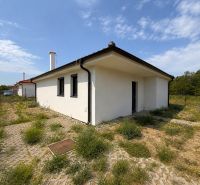 A family house in Most pri Bratislave, white exterior, fenced yard, partially grassed plot.