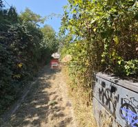 Plots - housing in Modra with an overgrown road and graffiti on the electrical box.