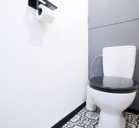 A bathroom with black and white tiles and toilet paper in a two-room apartment.