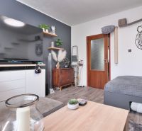 A bright living room with a large TV, decorations, and a wooden-patterned floor in a two-room apartment.