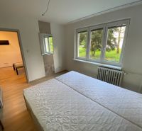 A bright bedroom in a 2-room apartment with a window and a wooden decor floor.