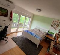 Bedroom in a family house with a bed, a desk, and a wooden decor floor.
