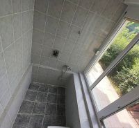 A shower corner with tiles and a shower chair in a family house.