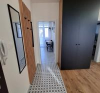 A hallway in a 3-room apartment with a combination of tiles and flooring with a wooden decor.