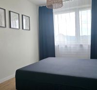 A bedroom in a three-room apartment with frames on the wall and a floor with a wooden decor.