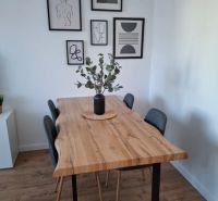 A dining table with a wood finish and decorative paintings in a 3-room apartment.