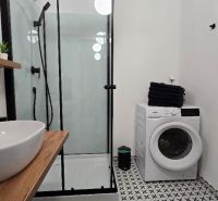 Bathroom with a sink, shower, and washing machine in a 3-room apartment. Black and white tiles.
