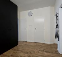 In the 3-room apartment, there is a hallway with a wooden decor floor and dark furniture.