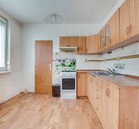 A kitchen in a 3-room apartment with a wooden decor floor and a white gas stove.