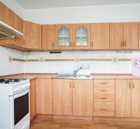 A kitchen with light furniture and a wooden decor floor in a 3-room apartment.