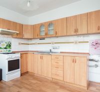 A kitchen in a 3-room apartment with a wooden decor floor and light furniture.