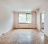 Living room in a three-room apartment with a wooden decor floor and a large window.