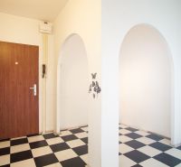 Entrance hall in a 3-room apartment with black and white tiles and wooden doors.