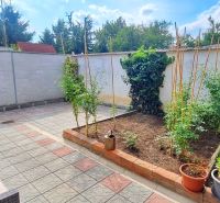 The garden of a family house in Bodona, Piešťany with plants and rattan seating.