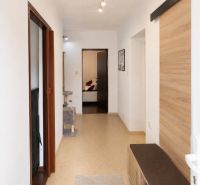 A hallway in a family house with wooden decor on the wall and simple lighting.