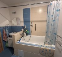 A bathroom with a bathtub and blue tiles in a three-room apartment.