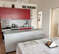 A kitchen with a table, cabinets, and a floor with a wood decor in a 3-room apartment.