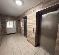 The entrance hall with elevators, wooden decor and tiles, typical for a 3-room apartment.