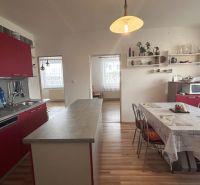 A kitchen in a 3-room apartment with red cabinets and a wooden decor floor.