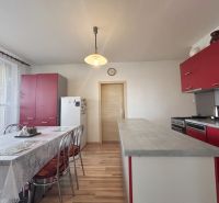A kitchen in a 3-room apartment with red cabinets and a wood-patterned floor.