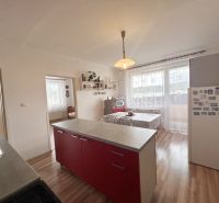 A kitchen with a dining area in a three-room apartment with a wooden decor floor.