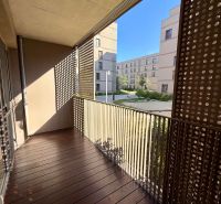 Balcony of a 2-room apartment with a wooden decor floor and a view of the courtyard.