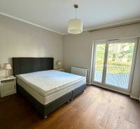 Bedroom in a 2-room apartment with a bed, a lamp, and a wooden decor floor.