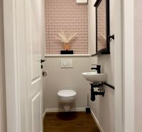 A toilet with a wall featuring a geometric pattern, a mirror, and a floor with a wooden decor.