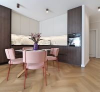 A kitchen in a 3-room apartment with a wood-patterned floor and pink chairs.