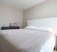 A bedroom in a 3-room apartment with a white bed and a nightstand.