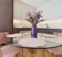 Dining area with a round table and pink chairs in a 3-room apartment.