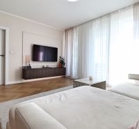 Living room in a 3-room apartment with a sofa, TV, and wooden decor flooring.
