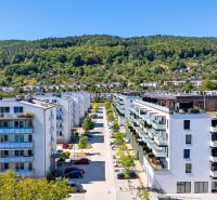 Púchov, Dlhé lúky: Row housing with apartments, green hills and greenery in the background.