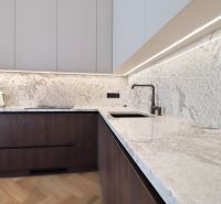 A kitchen in a 3-room apartment with marble countertops and a wood-patterned floor.
