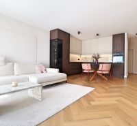 Living room with a white sofa, kitchenette, and wooden decor flooring.