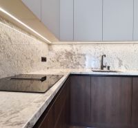 A kitchen with light stone cladding and a cooktop in a 3-room apartment.
