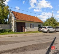 A family house in Budmerice with a red roof, cars parked in front of the house.