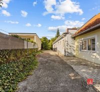 The exterior of a family house in Budmerice, a paved path surrounded by greenery and a fence.