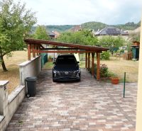 A garden with a carport at a family house in Medzibrod, surrounded by greenery.