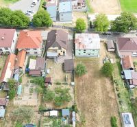 Aerial view of a row of family houses in Medzibrod with gardens and yards.