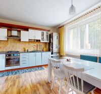 A kitchen in a family house with a wooden decor floor and yellow curtains.