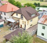 A family house in Medzibrod with two roofs and a small lawn in the garden.