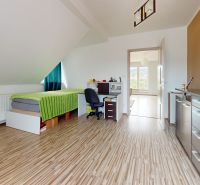 A bright room with a bed, a desk, and a wooden floor decor in a family house.